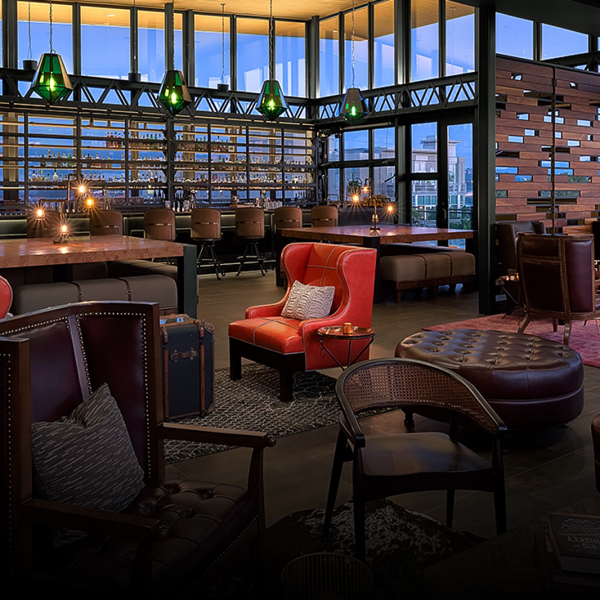 Cozy rooftop lounge with leather chairs, wooden tables, and dim lighting.